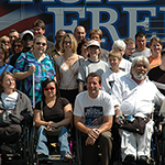 Rick Cardenas in a group photo with the disability community, in front of the “Road To Freedom” bus.