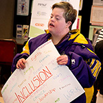 Disability advocate holding a poster. The most prominent word, among a group of such, is Inclusion.