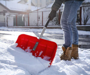 Closeup of a person shoveling snow off a sidewalk
