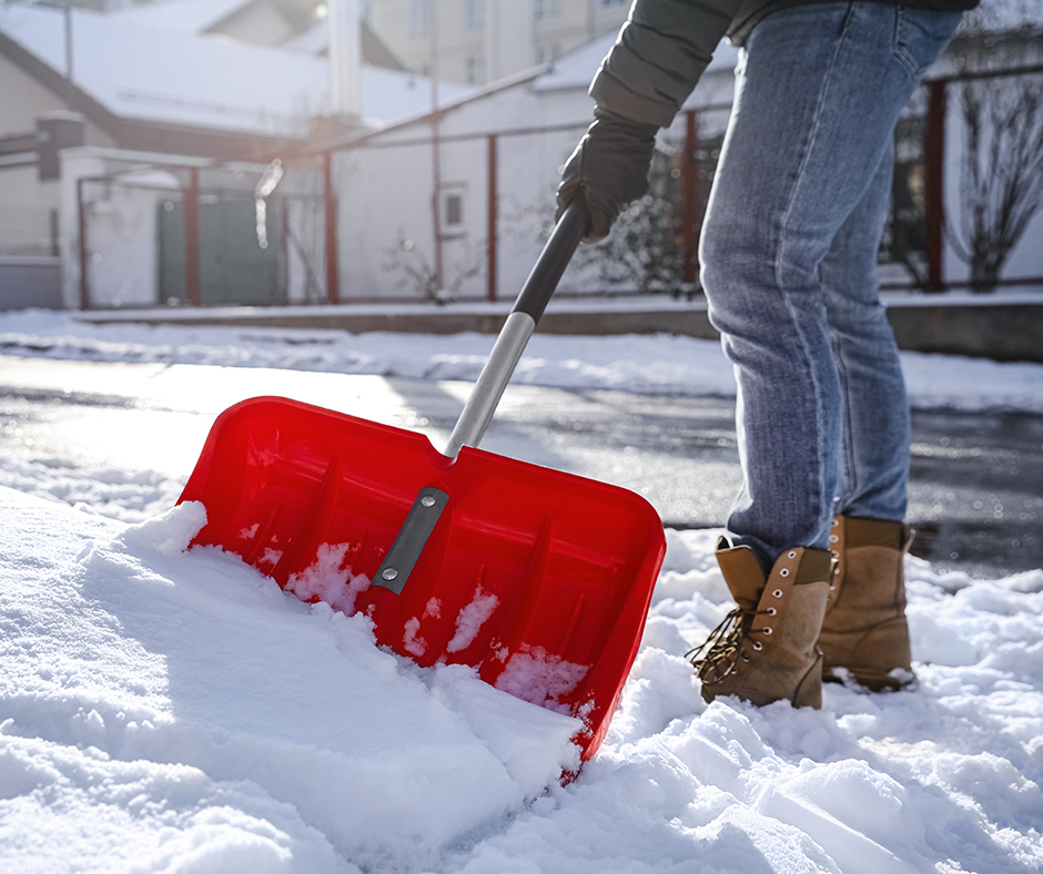 Closeup of someone shoveling snow off a sidewalk