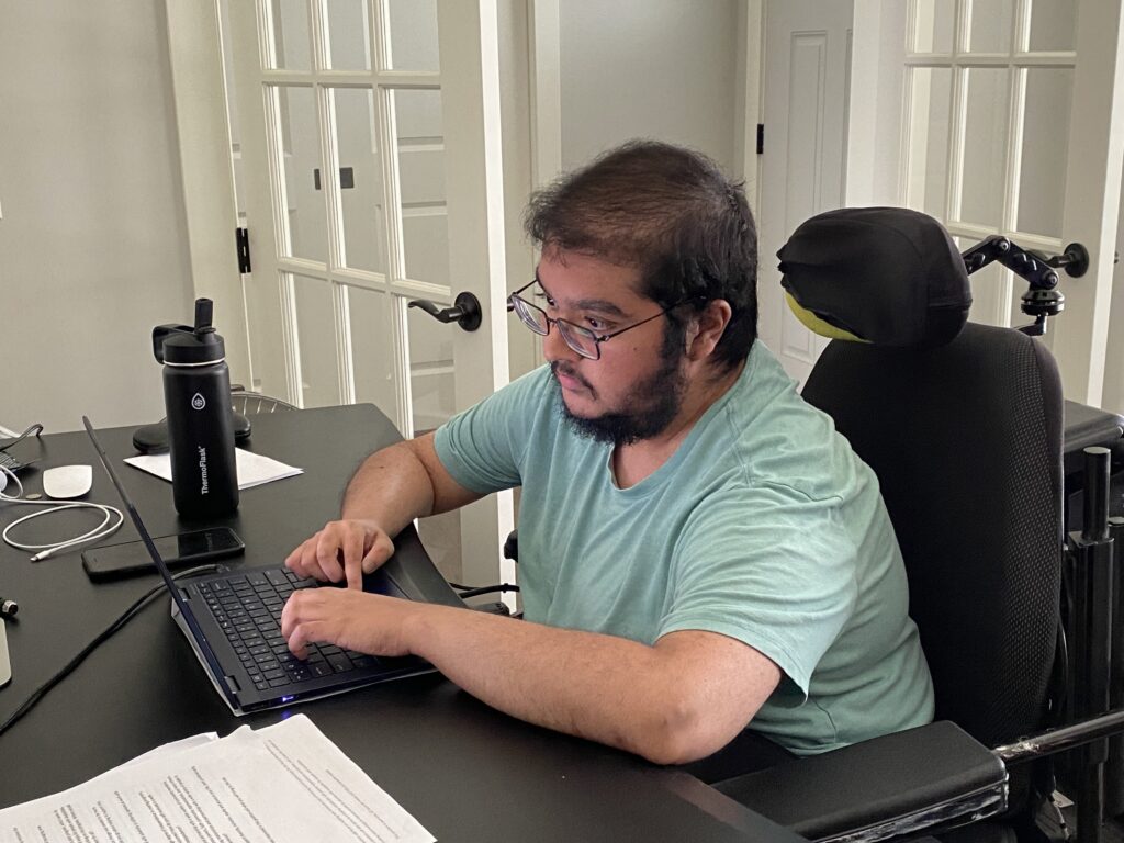 Sumukha Terakanambi in his wheelchair working at his laptop