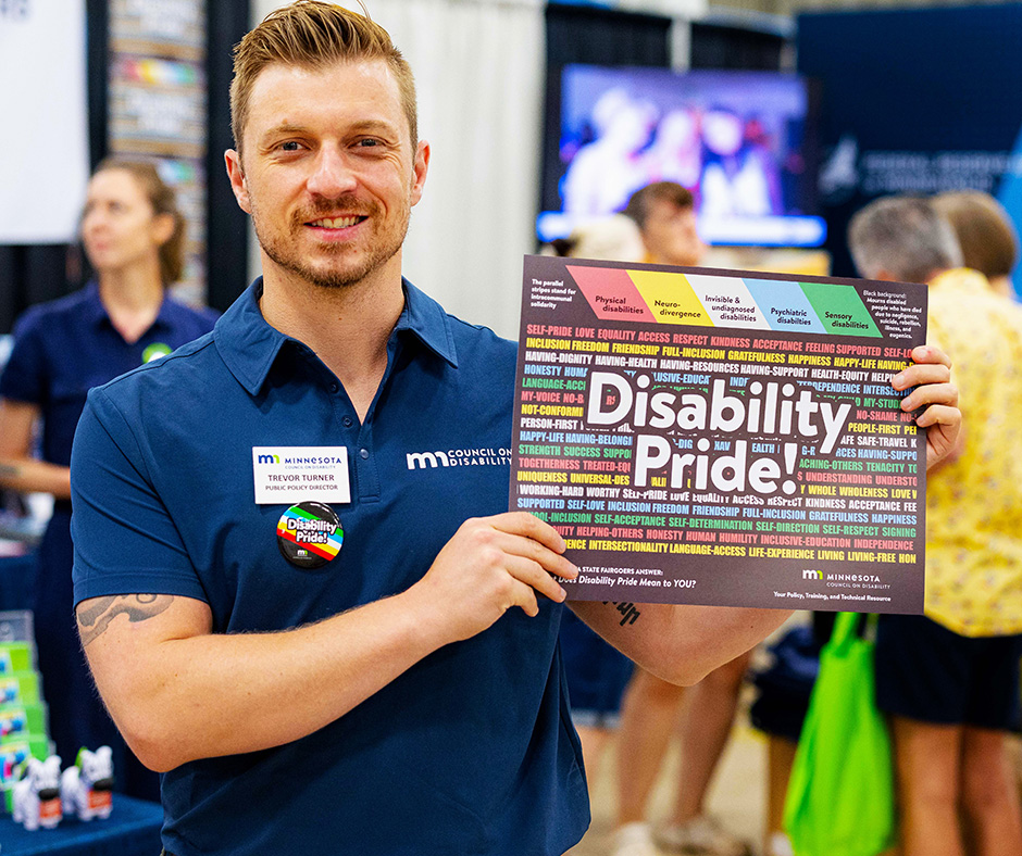 Public Policy Director Trevor Turner holds a poster with the text "Disability Pride!" Behind that are words associated with disability pride, including "supported," "inclusion," and "independence."
