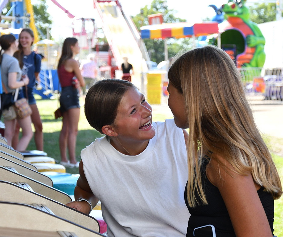 Two children playing a game at the Kandiyohi County Fair and smiling.