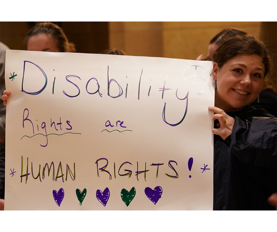 Woman holding a sign that reads, "Disability Rights are HUMAN RIGHTS!"