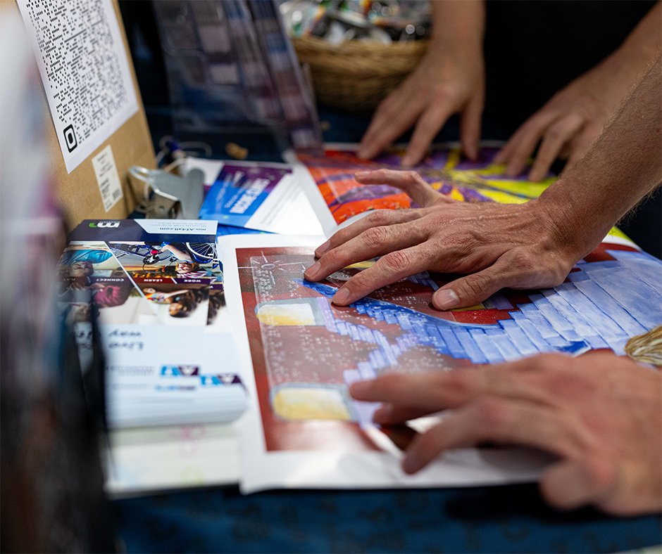 Close-up of a person reading a Braille overlay on top of an art poster.