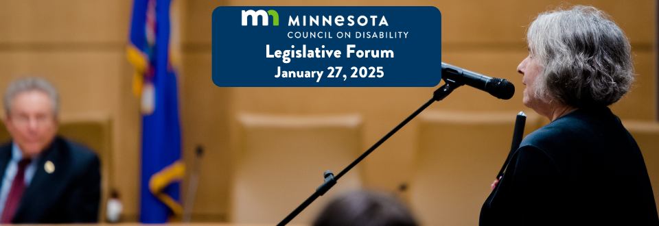 An older woman with gray hair holding a white cane speaks into a microphone at at an event, with a blurred man seated in the background. A banner top center reads: 'Minnesota Council on Disability Legislative Forum, January 27, 2025.' A Minnesota state flag is partially visible in the background.